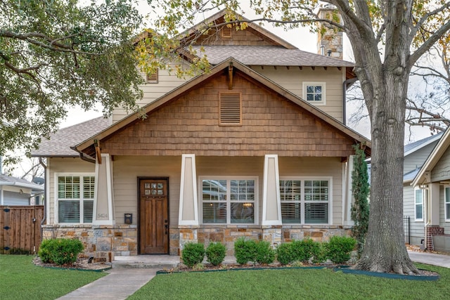 craftsman inspired home featuring a porch, stone siding, and roof with shingles