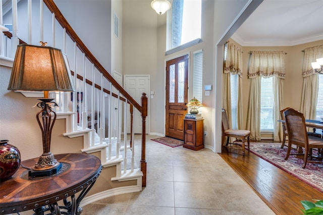 entrance foyer featuring a high ceiling, ornamental molding, and light tile patterned floors