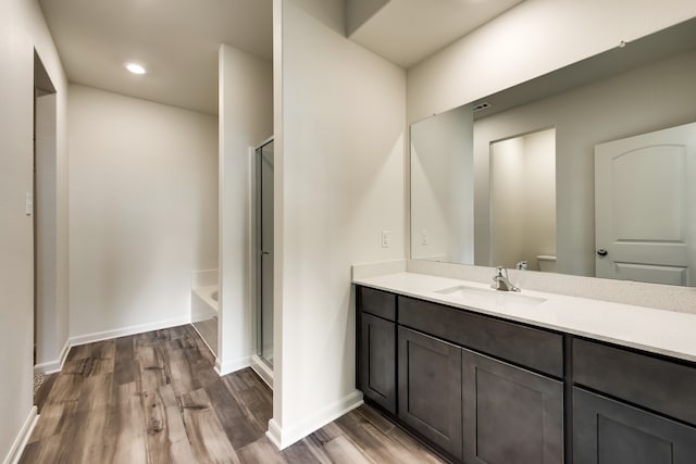 bathroom with vanity, hardwood / wood-style flooring, and plus walk in shower