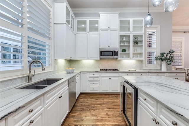 kitchen featuring sink, ornamental molding, stainless steel appliances, beverage cooler, and white cabinets