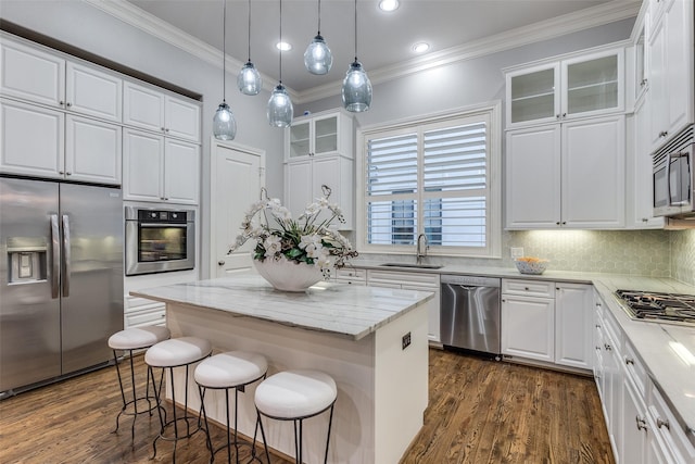 kitchen with white cabinetry, sink, stainless steel appliances, and a kitchen island