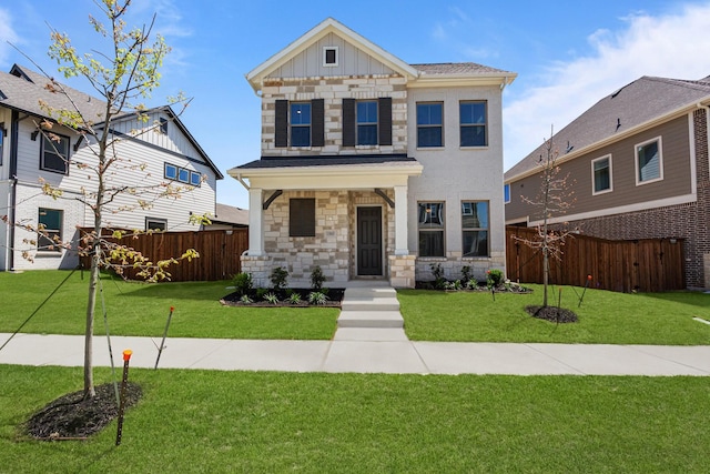 view of front facade with board and batten siding, fence, stone siding, and a front lawn