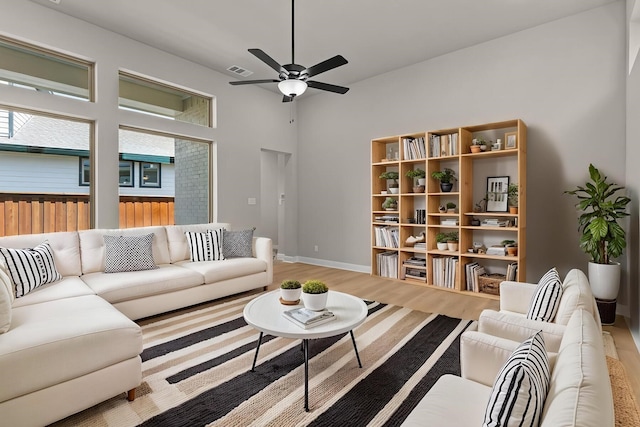 living room featuring wood finished floors, a ceiling fan, visible vents, and a healthy amount of sunlight