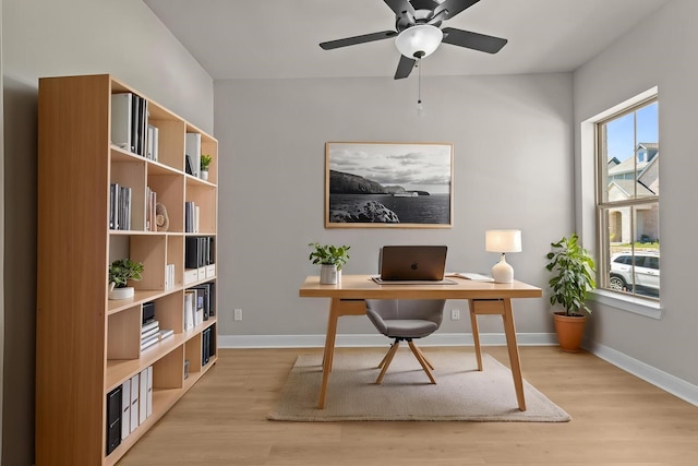 home office featuring baseboards, light wood finished floors, and a ceiling fan