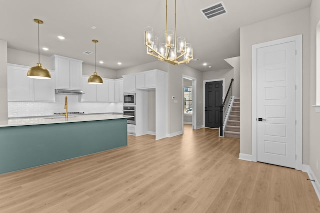 kitchen with light wood-type flooring, light countertops, white cabinets, visible vents, and stainless steel appliances