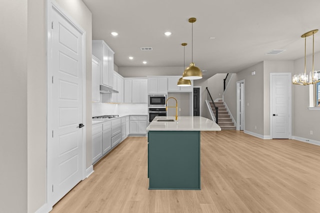 kitchen featuring stainless steel appliances, visible vents, and light wood-type flooring