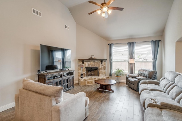 living room featuring hardwood / wood-style floors, a stone fireplace, high vaulted ceiling, and ceiling fan