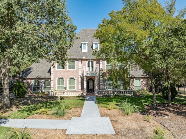 colonial house with brick siding, roof with shingles, and a front yard