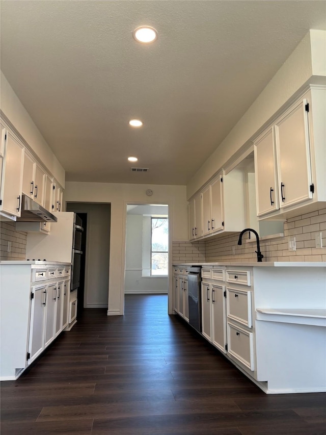 kitchen with dark wood-style floors, light countertops, visible vents, white cabinetry, and dishwasher