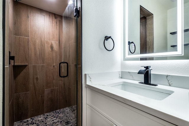 full bathroom featuring a textured wall, a shower stall, and vanity