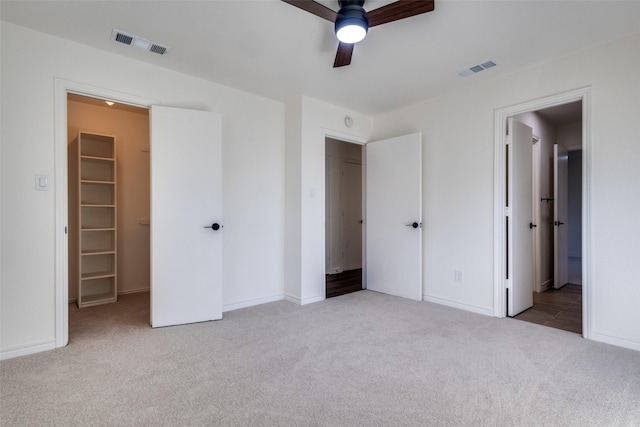 unfurnished bedroom featuring visible vents, a closet, light colored carpet, and a spacious closet