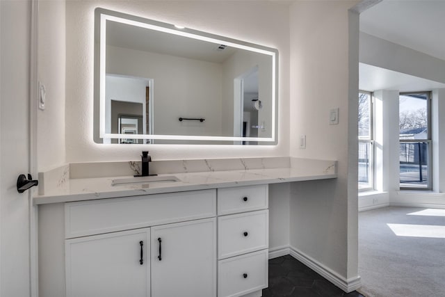 bathroom with a textured wall, vanity, and baseboards