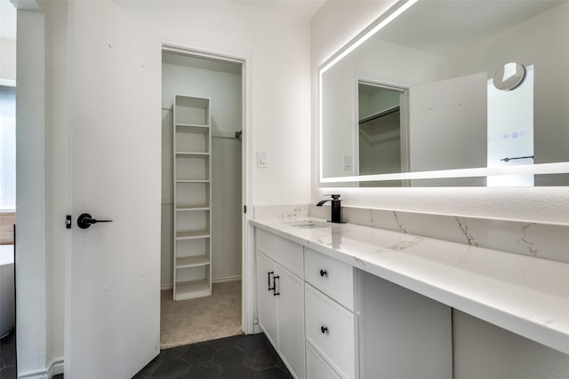 full bath with a spacious closet, vanity, and tile patterned floors