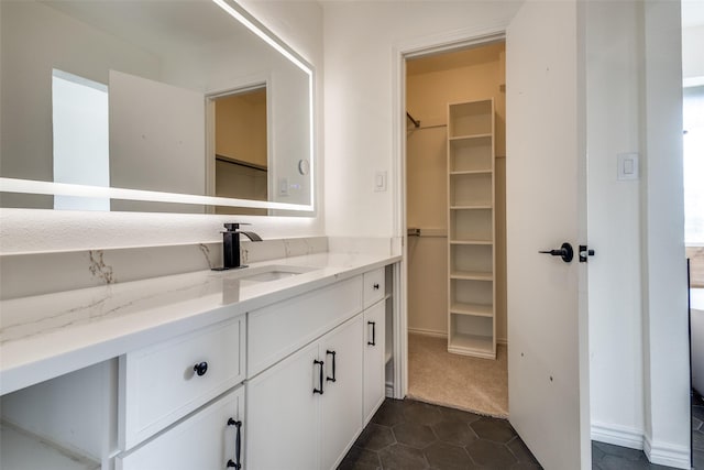 bathroom featuring a spacious closet, vanity, and tile patterned floors