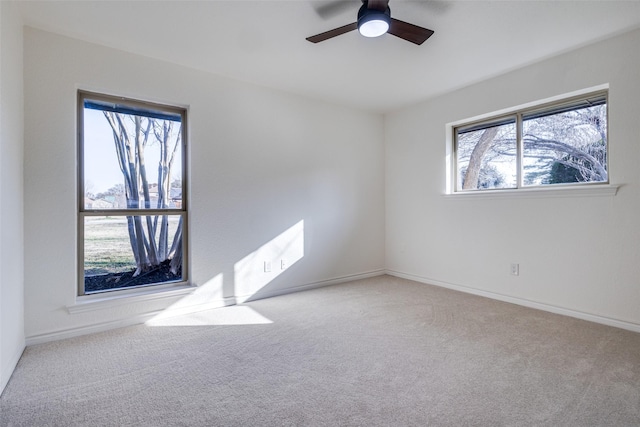 spare room featuring light carpet, ceiling fan, and baseboards