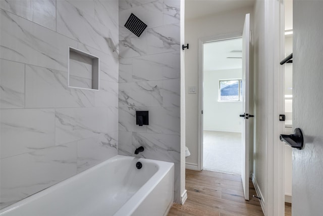 bathroom with baseboards, wood finished floors, and bathing tub / shower combination