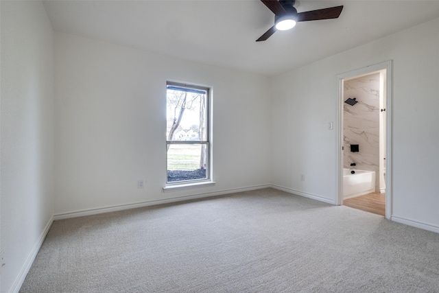 empty room with baseboards, a ceiling fan, and light colored carpet