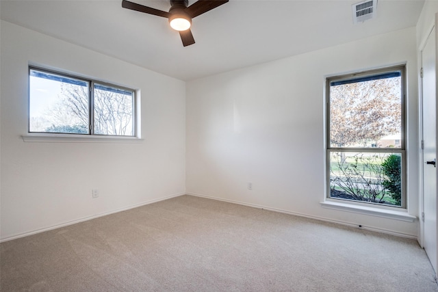 spare room featuring visible vents, ceiling fan, light carpet, and baseboards