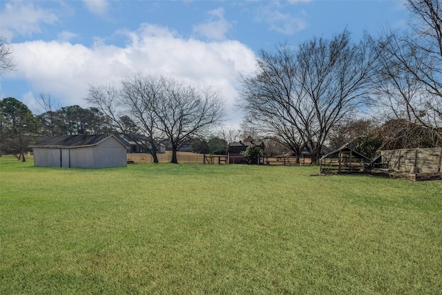 view of yard featuring a rural view, an outdoor structure, and fence