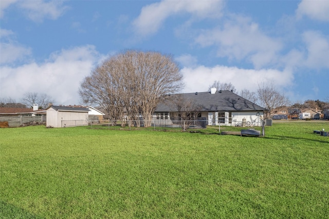 view of yard with fence, an outdoor structure, and a storage unit