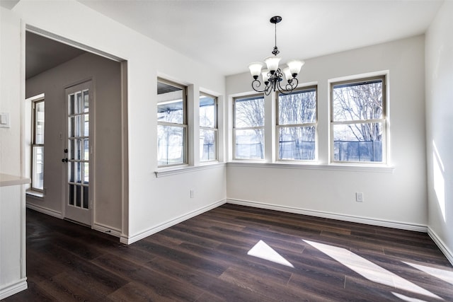 unfurnished dining area with a notable chandelier, baseboards, and dark wood-type flooring