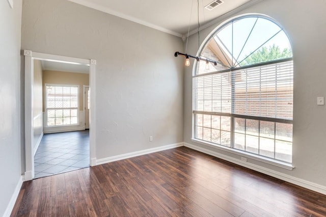 empty room featuring ornamental molding, dark wood-style flooring, and baseboards