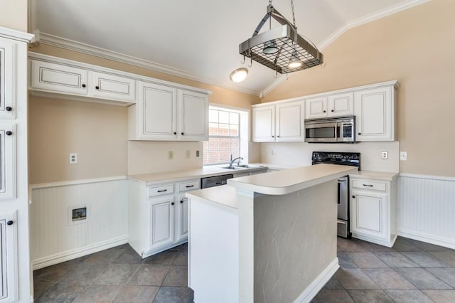 kitchen with a kitchen island, white cabinetry, light countertops, appliances with stainless steel finishes, and wainscoting