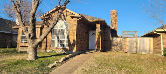 view of front of property with brick siding, a chimney, and a front lawn