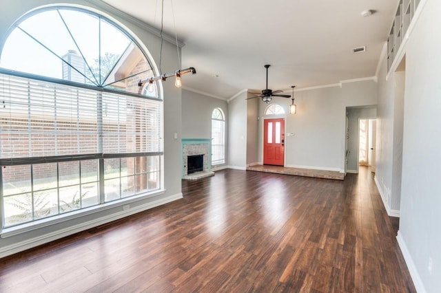 unfurnished living room with baseboards, visible vents, dark wood-style floors, crown molding, and a brick fireplace