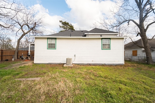 back of house with central AC unit and a lawn