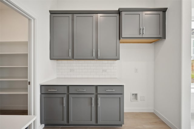 kitchen featuring tasteful backsplash, gray cabinets, and light wood-type flooring