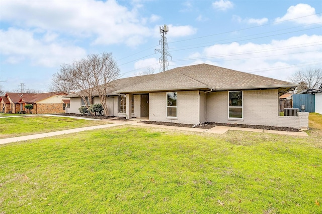 view of front of home featuring central air condition unit, brick siding, a shingled roof, fence, and a front yard