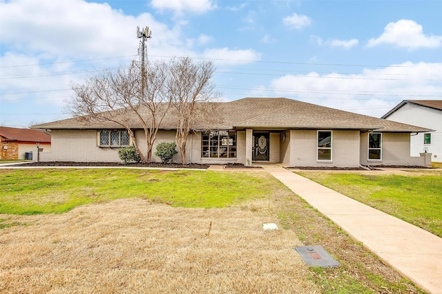 ranch-style home featuring a front lawn, roof with shingles, and brick siding