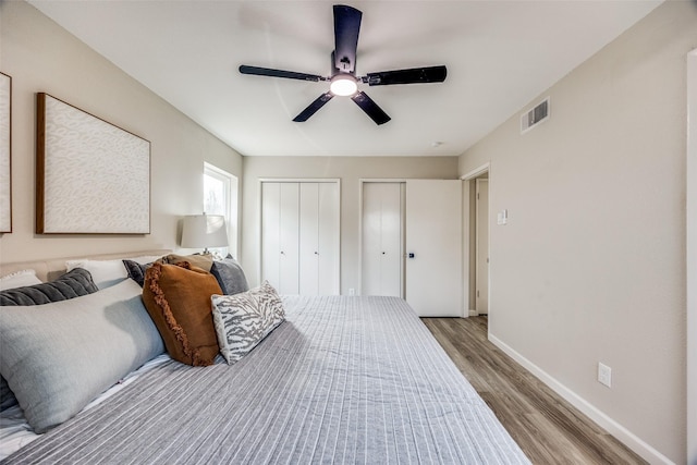 bedroom featuring two closets, ceiling fan, and light hardwood / wood-style flooring