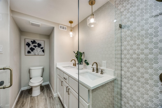 bathroom with hardwood / wood-style flooring, vanity, walk in shower, and toilet