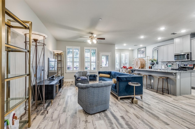 living room featuring ceiling fan and light hardwood / wood-style flooring