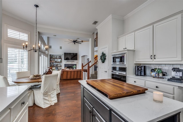 kitchen with tasteful backsplash, white cabinets, dark hardwood / wood-style flooring, stainless steel appliances, and crown molding