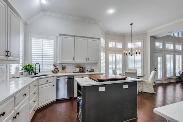 kitchen with ornamental molding, white cabinets, a kitchen island, decorative light fixtures, and stainless steel dishwasher