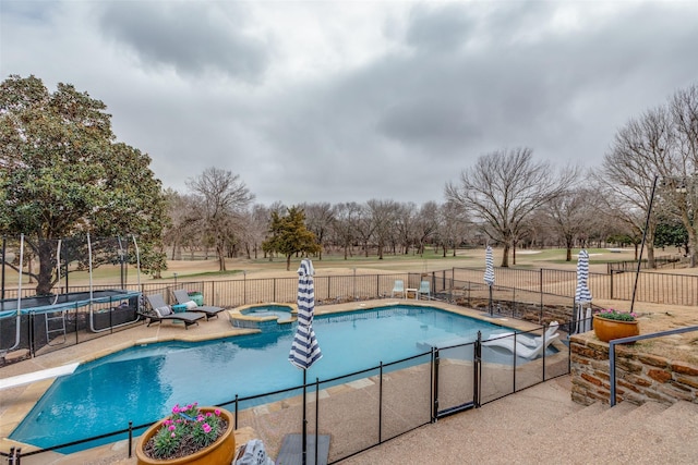 view of pool featuring a trampoline, a patio area, a diving board, and an in ground hot tub