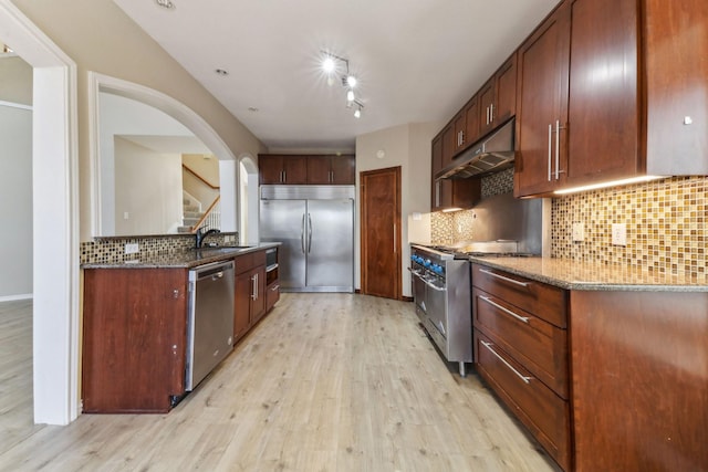 kitchen with tasteful backsplash, stone countertops, and premium appliances