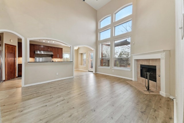 unfurnished living room with a fireplace, high vaulted ceiling, and light hardwood / wood-style flooring