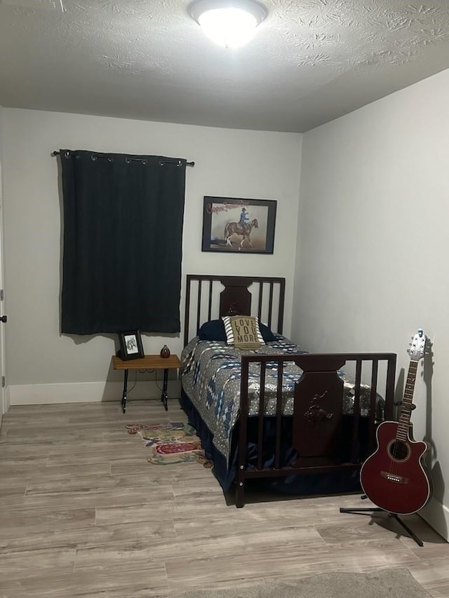 bedroom with a textured ceiling and light wood-type flooring