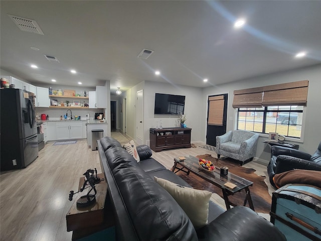 living room featuring sink and light hardwood / wood-style flooring