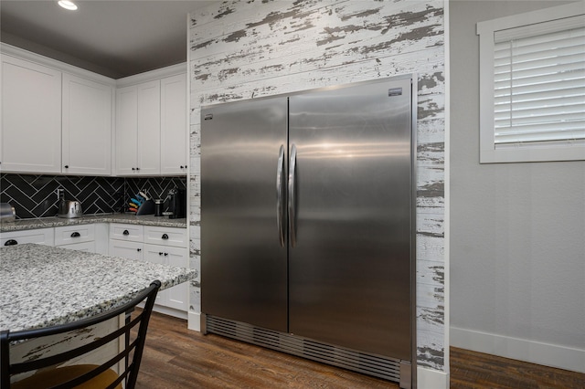 kitchen with white cabinetry, stainless steel built in fridge, dark wood-type flooring, and light stone countertops