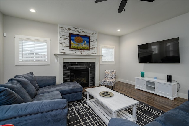 living room featuring a tiled fireplace, dark wood-type flooring, and ceiling fan