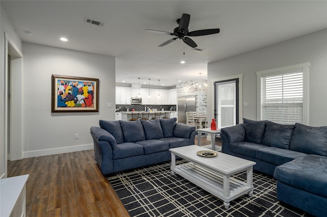 living room featuring dark wood-type flooring and ceiling fan with notable chandelier