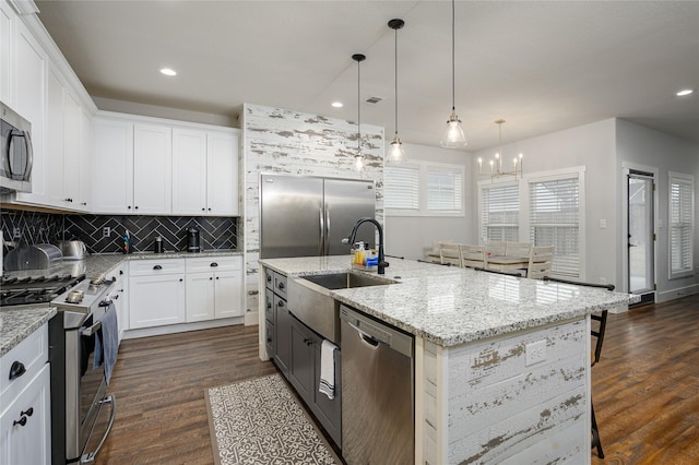 kitchen featuring hanging light fixtures, an island with sink, white cabinets, and appliances with stainless steel finishes