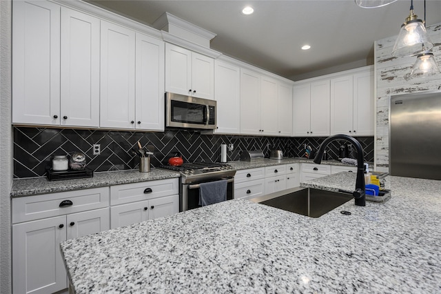 kitchen with white cabinetry, sink, hanging light fixtures, and appliances with stainless steel finishes