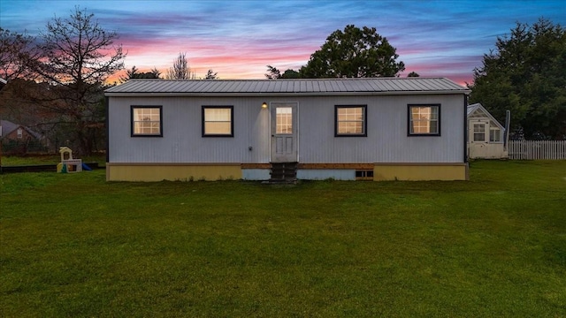 back house at dusk featuring a lawn