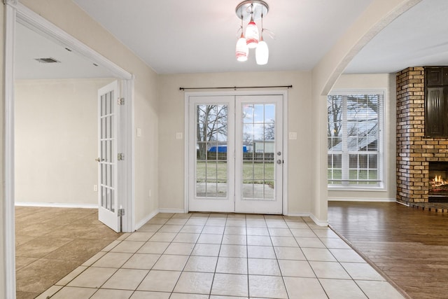 entryway with a brick fireplace and light tile patterned floors